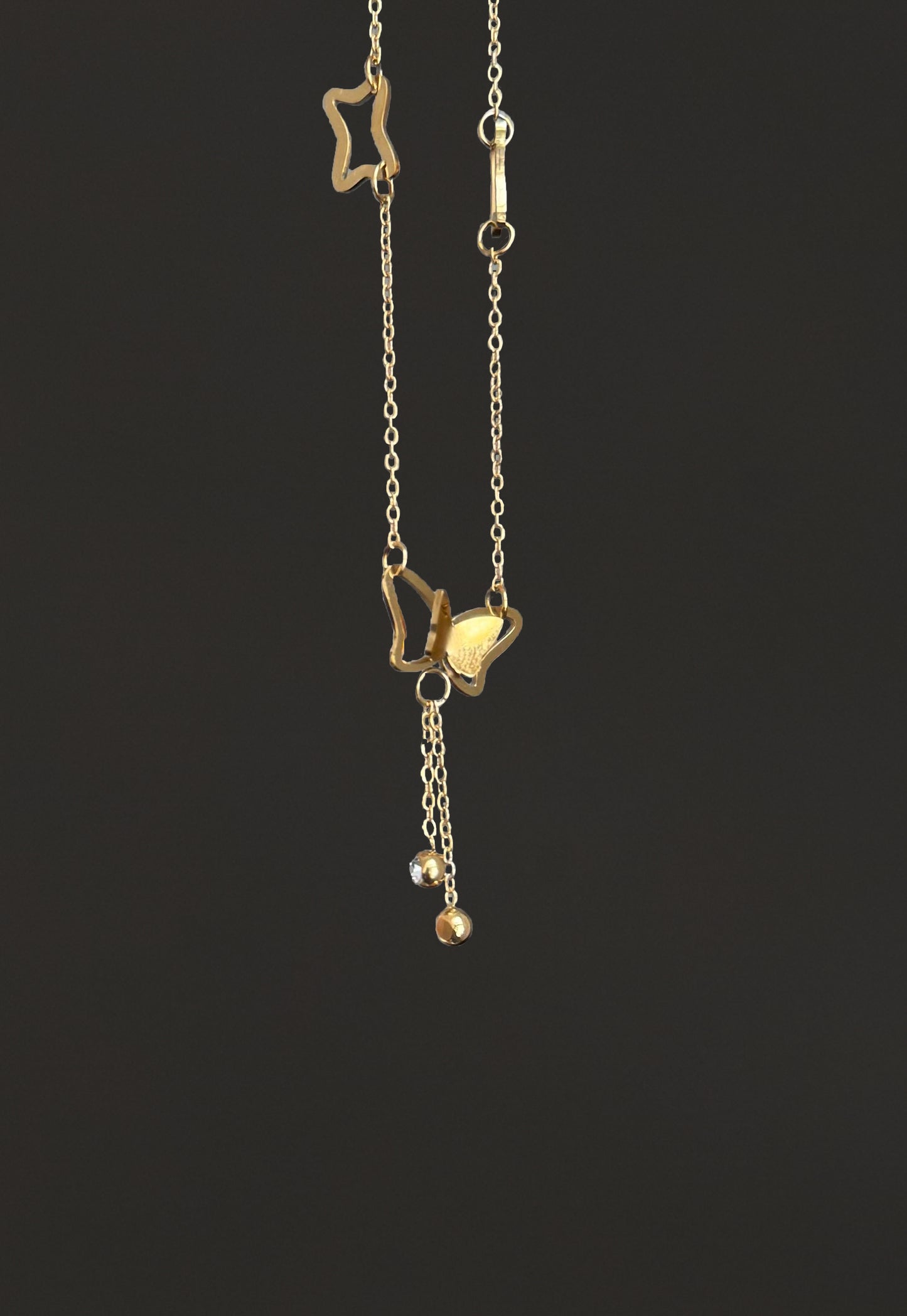 Gold necklace with star and heart pendants on a black background