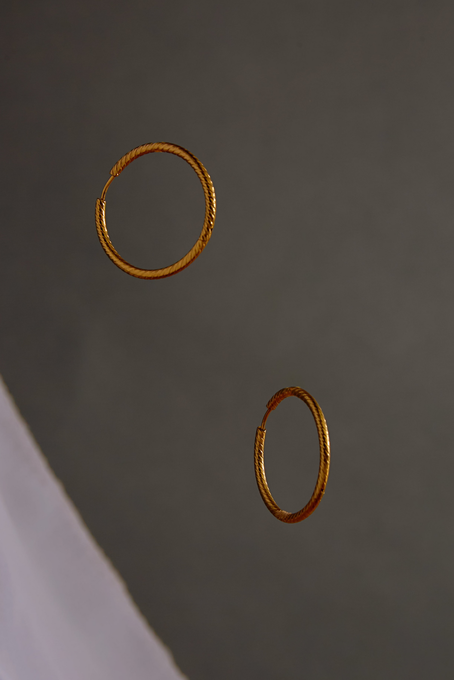 Two gold hoop earrings on a dark gray background