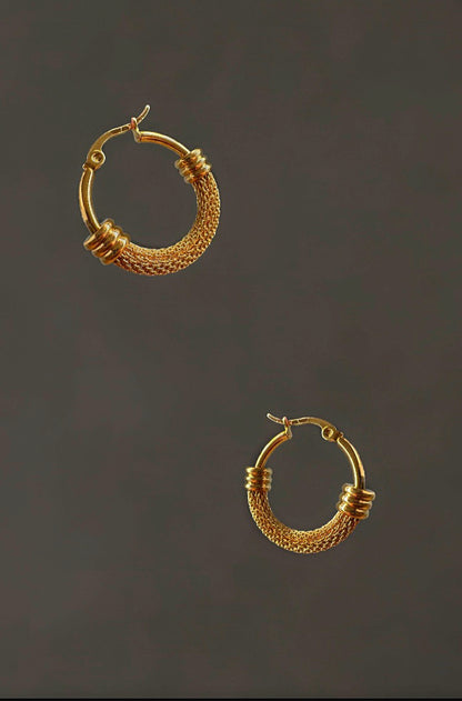 Pair of gold hoop earrings on a dark background