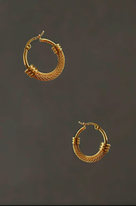 Pair of gold hoop earrings on a dark background