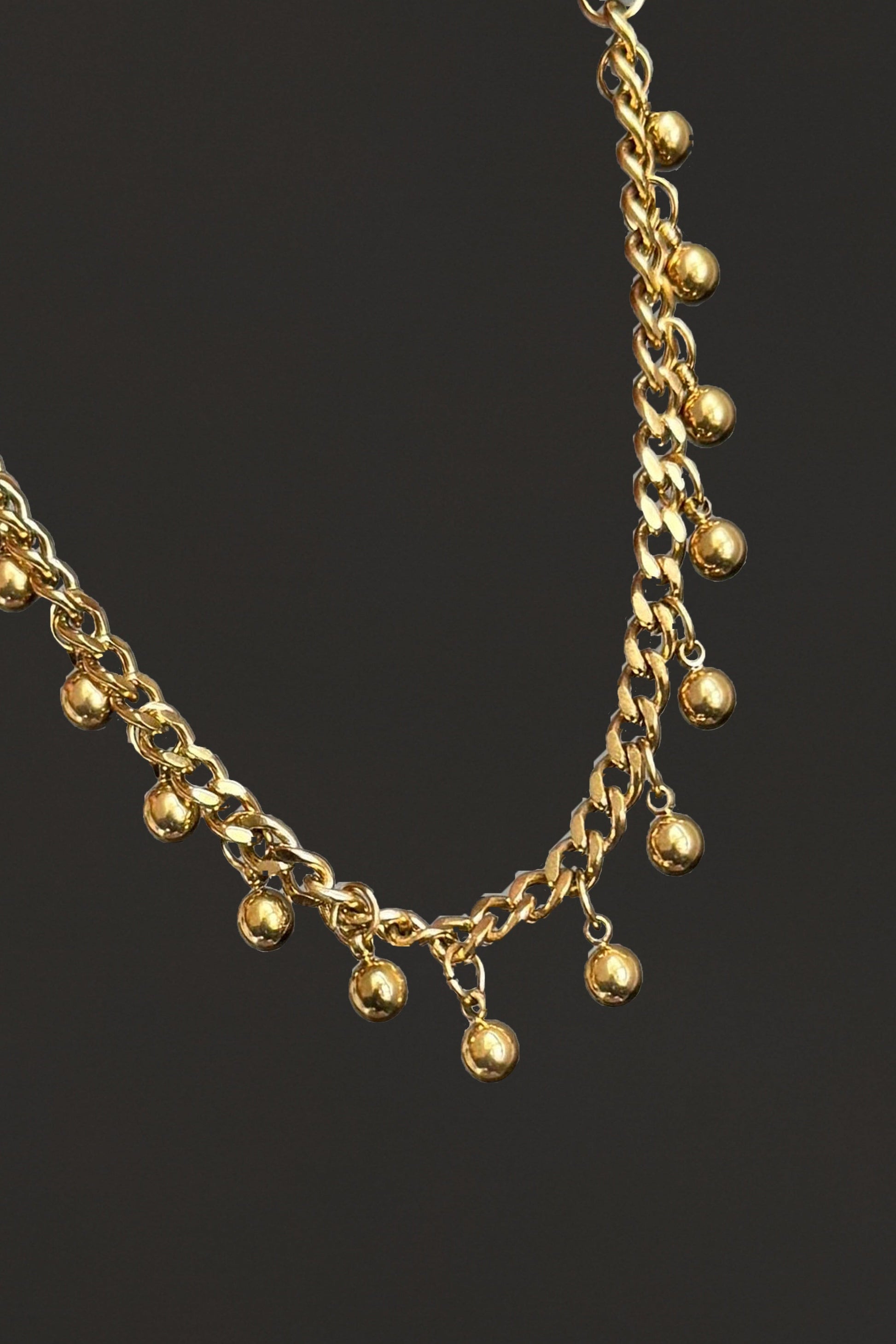 Gold chain bracelet / anklet with small golden beads on a black background