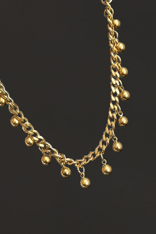 Gold chain bracelet / anklet with small golden beads on a black background